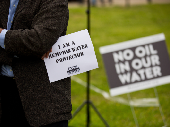 A person holds a small sign that says, "I am a Memphis water protector."