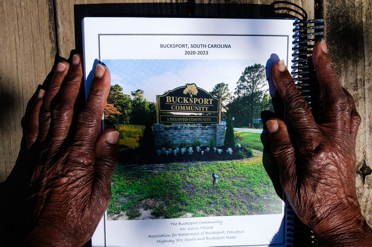 Close up photo of an older Black person's hands on a computer-printed booklet titled 