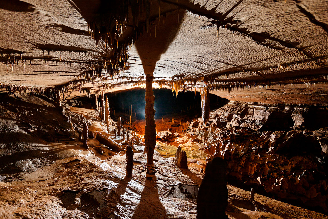 A wide angle shows a room where stalactites from the ceiling and stalagmites from the floor meet in the middle.