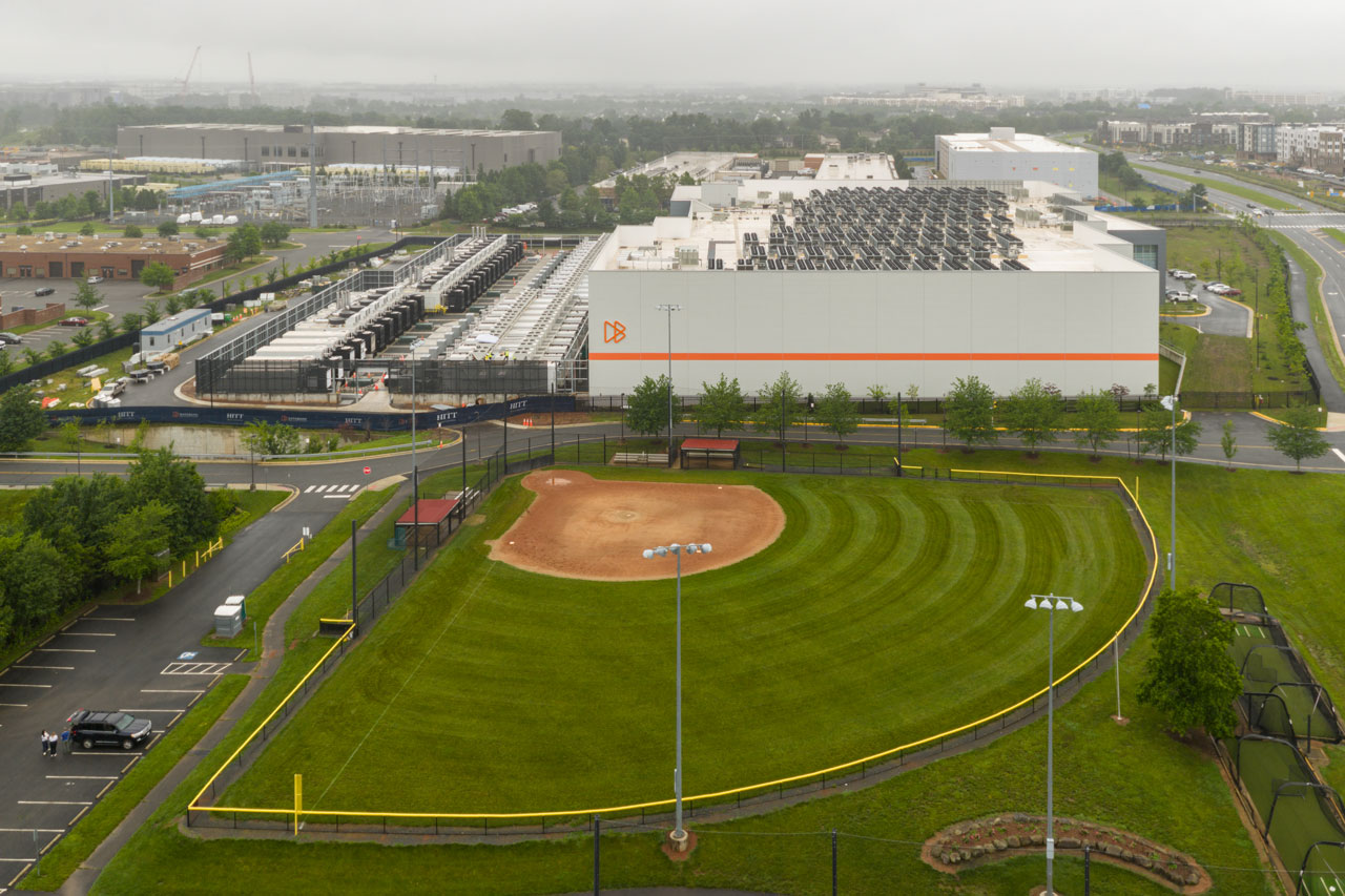 An aerial view shows a large data center butting up against a baseball field.